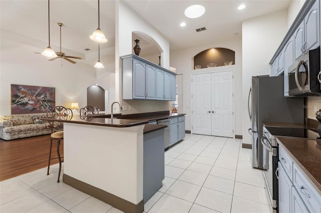 kitchen with a kitchen bar, dark countertops, visible vents, and appliances with stainless steel finishes