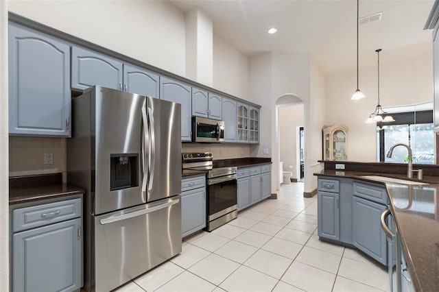 kitchen with light tile patterned floors, backsplash, stainless steel appliances, and a sink