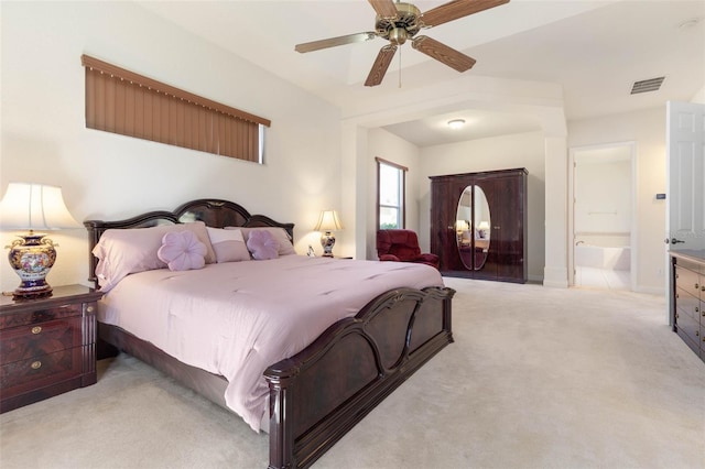 bedroom featuring baseboards, visible vents, ceiling fan, ensuite bathroom, and light colored carpet