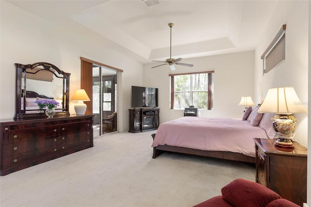 carpeted bedroom featuring visible vents, a raised ceiling, and ceiling fan