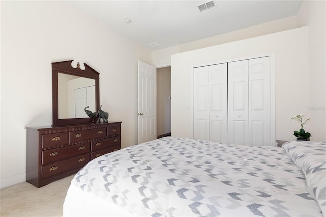 bedroom with light colored carpet, visible vents, and a closet