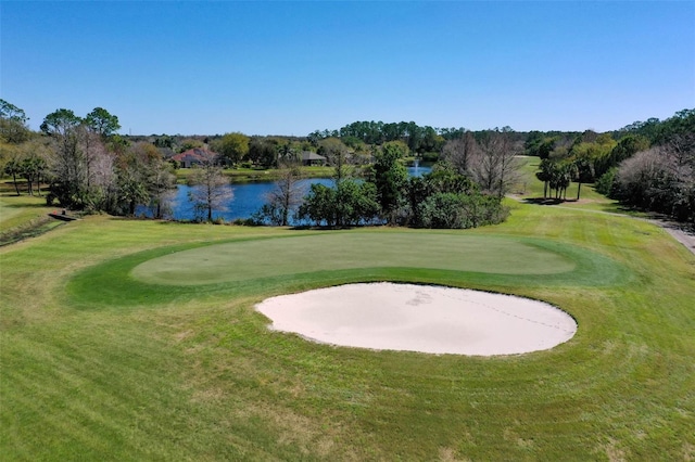 view of property's community with a water view, a lawn, and view of golf course