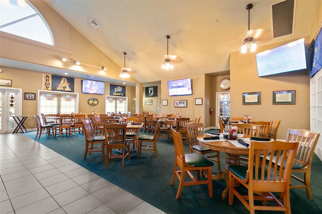 tiled dining space featuring plenty of natural light, high vaulted ceiling, visible vents, and a ceiling fan