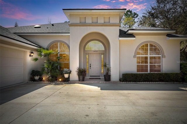 doorway to property with a shingled roof and stucco siding