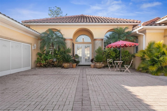 doorway to property featuring a tiled roof, french doors, and stucco siding