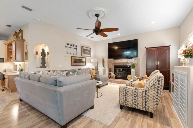 living area featuring recessed lighting, a tile fireplace, visible vents, and light wood-style floors