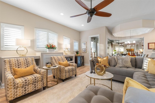 living area featuring ceiling fan with notable chandelier, light wood-type flooring, baseboards, and recessed lighting