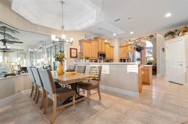 dining room featuring arched walkways, an inviting chandelier, a tray ceiling, light tile patterned flooring, and recessed lighting