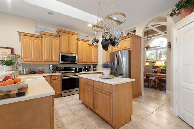 kitchen featuring stainless steel appliances, a sink, light countertops, and a center island