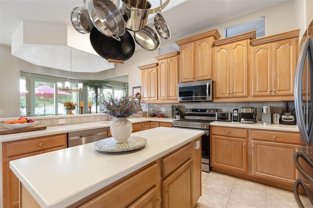 kitchen featuring light tile patterned floors, light countertops, backsplash, appliances with stainless steel finishes, and a chandelier