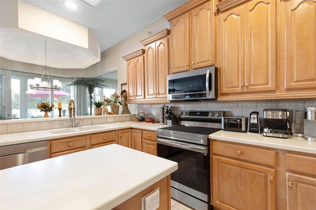 kitchen featuring a chandelier, a sink, light countertops, appliances with stainless steel finishes, and tasteful backsplash