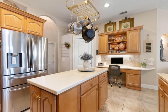 kitchen featuring visible vents, decorative backsplash, built in study area, light countertops, and stainless steel refrigerator with ice dispenser