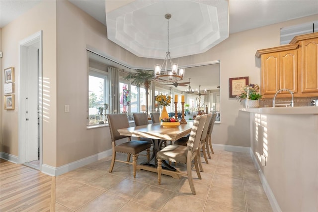 dining space featuring light tile patterned floors, a tray ceiling, baseboards, and an inviting chandelier