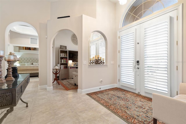 entryway featuring a high ceiling, baseboards, and light tile patterned flooring