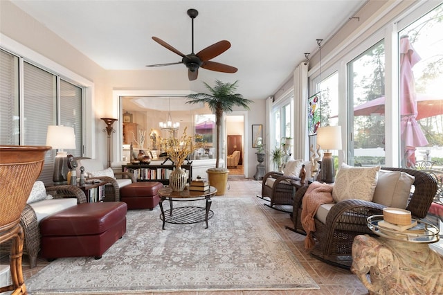 sunroom featuring ceiling fan with notable chandelier