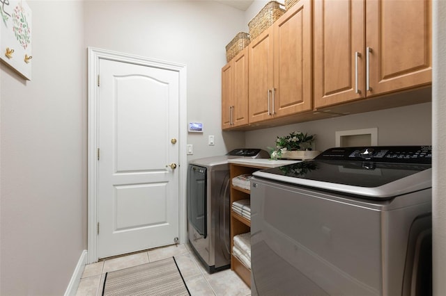 laundry room featuring cabinet space, washing machine and dryer, light tile patterned floors, and baseboards