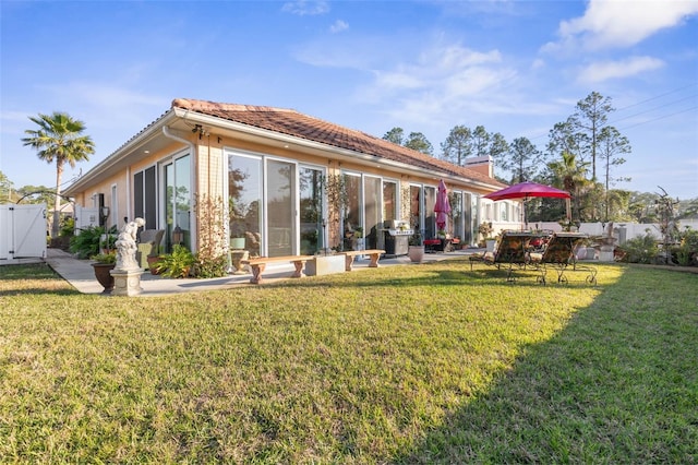 rear view of property featuring a patio area, a tiled roof, fence, and a yard