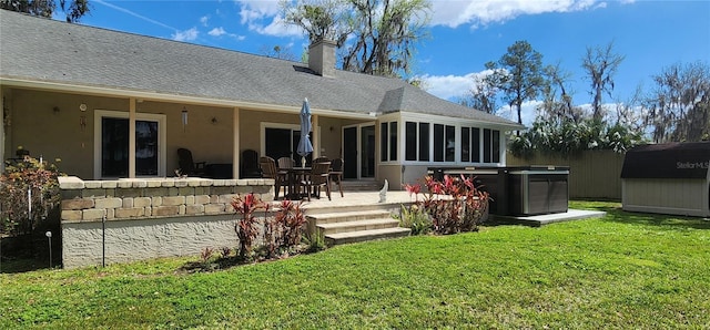 back of property with a patio, a sunroom, an outbuilding, a yard, and a shed