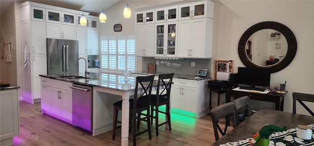 kitchen featuring stainless steel appliances, a sink, backsplash, and wood finished floors