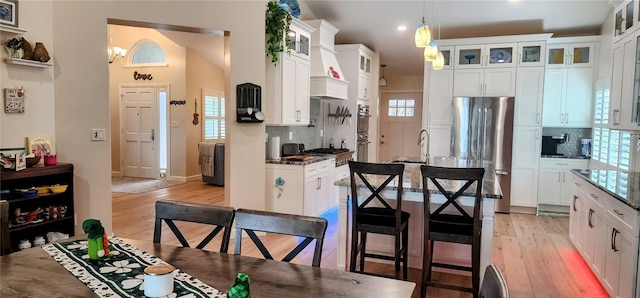 kitchen featuring backsplash, light wood-style floors, freestanding refrigerator, white cabinets, and a sink