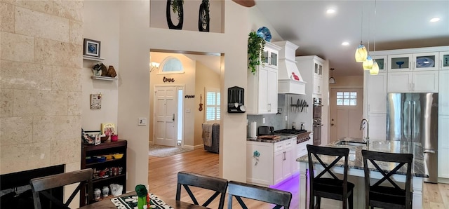 kitchen featuring tasteful backsplash, stainless steel refrigerator, white cabinets, and light wood-style floors