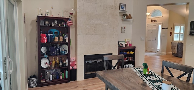 dining area featuring lofted ceiling, wood finished floors, and a tile fireplace