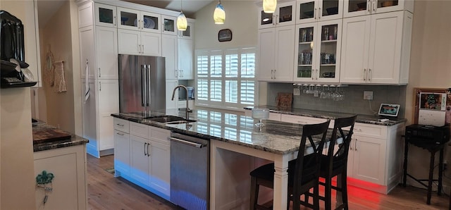 kitchen featuring appliances with stainless steel finishes, backsplash, a sink, and wood finished floors