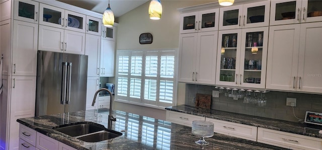 kitchen featuring high quality fridge, hanging light fixtures, a sink, white cabinetry, and backsplash