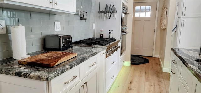 kitchen featuring appliances with stainless steel finishes, light wood-type flooring, white cabinets, and backsplash