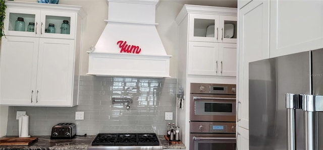 kitchen featuring white cabinets, glass insert cabinets, stainless steel appliances, and backsplash