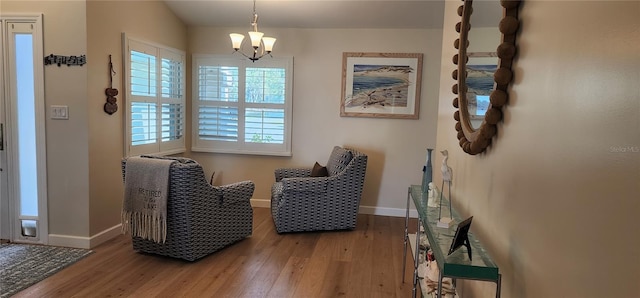 sitting room featuring an inviting chandelier, baseboards, and wood finished floors