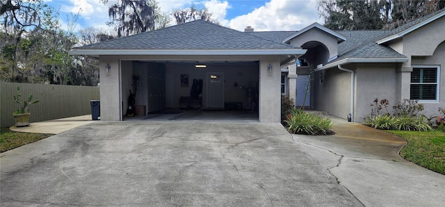 view of front facade featuring a garage, fence, concrete driveway, roof with shingles, and stucco siding