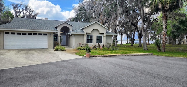 ranch-style home featuring a garage, a shingled roof, concrete driveway, stucco siding, and a front lawn