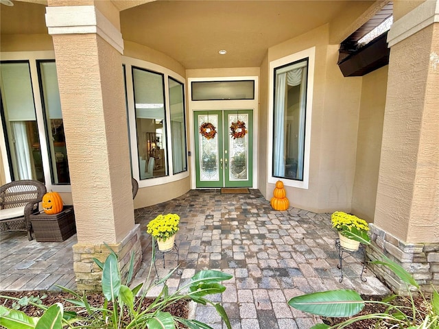 entrance to property with french doors, a patio area, and stucco siding