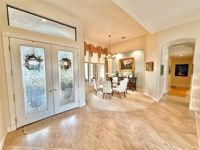 interior space with baseboards, visible vents, arched walkways, an inviting chandelier, and french doors