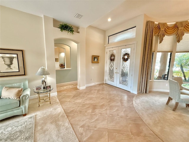 entrance foyer featuring arched walkways, french doors, visible vents, and baseboards