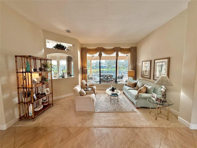 carpeted living area featuring a wealth of natural light, baseboards, and tile patterned floors