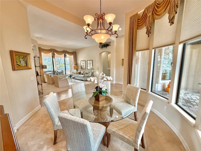 dining room featuring arched walkways, light tile patterned floors, a notable chandelier, light carpet, and baseboards