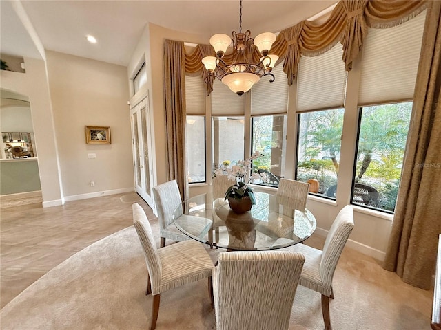 dining space featuring arched walkways, plenty of natural light, baseboards, and an inviting chandelier