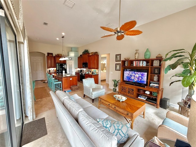 living area featuring arched walkways, visible vents, and ceiling fan