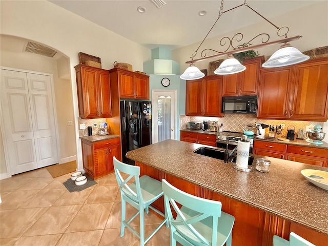 kitchen with tasteful backsplash, a breakfast bar area, visible vents, and black appliances