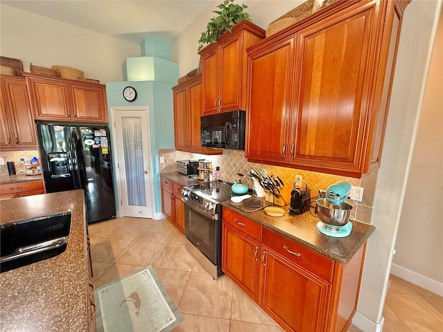 kitchen with light tile patterned floors, black appliances, brown cabinetry, and decorative backsplash