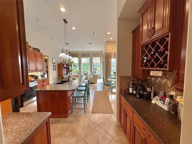 kitchen with a center island with sink, a breakfast bar area, stove, a sink, and backsplash