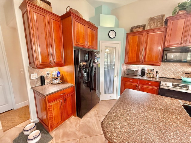 kitchen featuring light tile patterned floors, dark countertops, backsplash, brown cabinetry, and black appliances