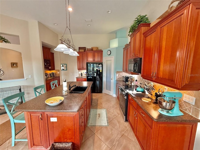 kitchen featuring decorative backsplash, a breakfast bar, brown cabinets, black appliances, and a sink