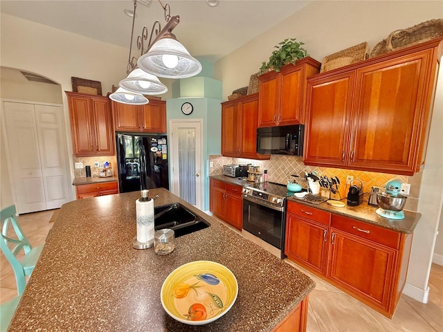 kitchen with tasteful backsplash, pendant lighting, a kitchen island with sink, and black appliances