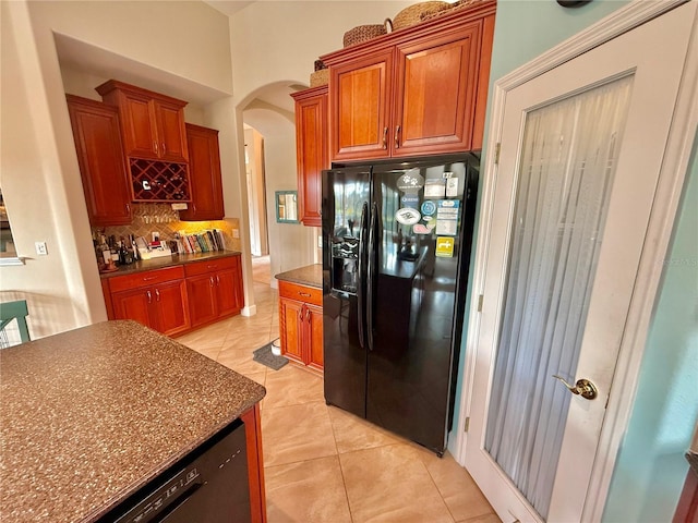 kitchen featuring arched walkways, backsplash, dark countertops, and black appliances