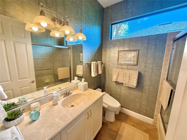 bathroom featuring toilet, vanity, baseboards, tiled shower, and tile patterned floors