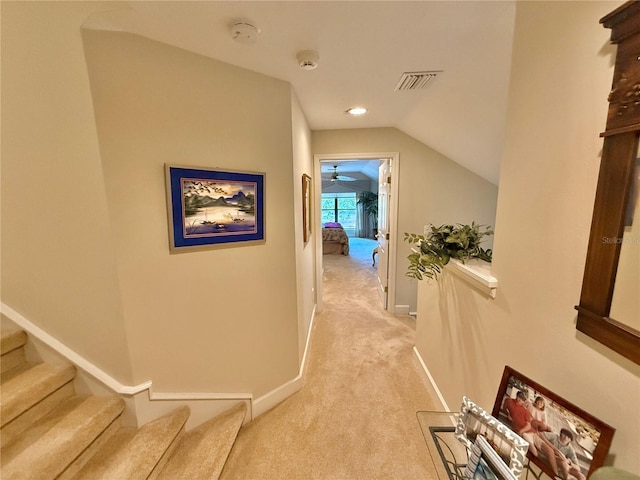 corridor featuring light carpet, baseboards, visible vents, lofted ceiling, and stairs