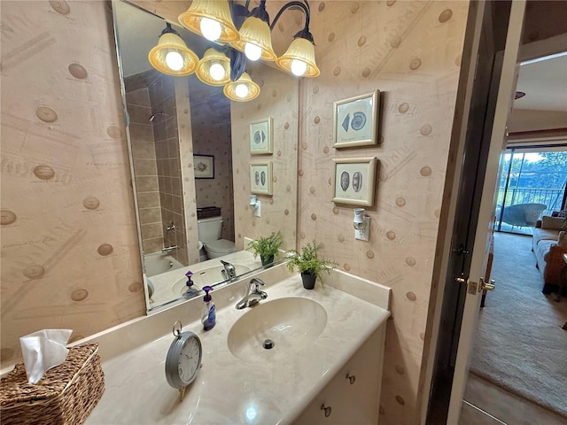 bathroom featuring vanity, toilet, and wallpapered walls